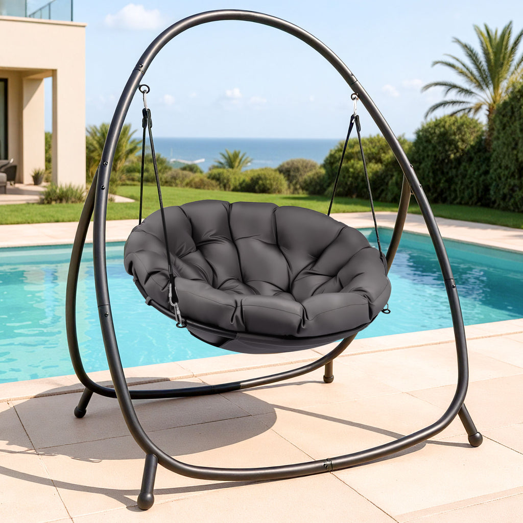Gray papasan chair with stand by a pool with ocean view