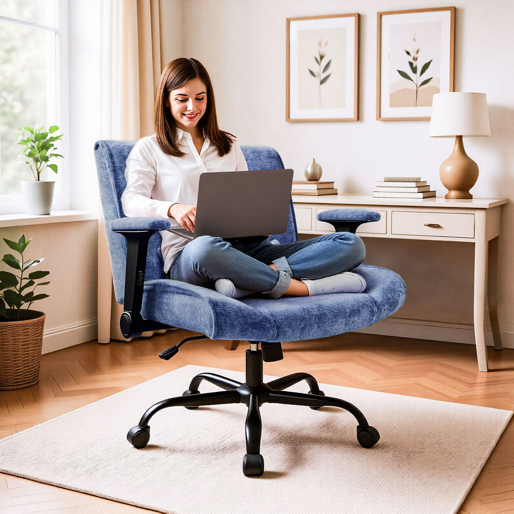 Woman using a laptop on a blue office chair in a home office setting